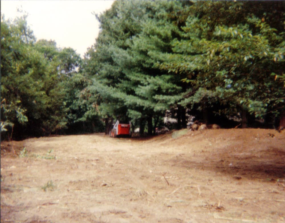 Compact loader grading and smoothing soil on a freshly cleared yard